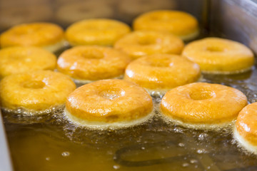 fried equal round doughnuts in deep-fryer