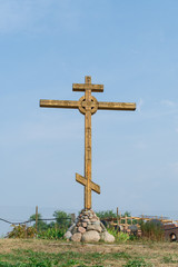A wooden cross stands high against the blue sky