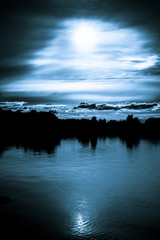 Moonlight in the clouds over a lake © ysign