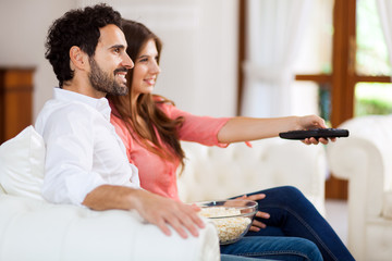 Fototapeta premium Young couple watching tv and eating pop-corn
