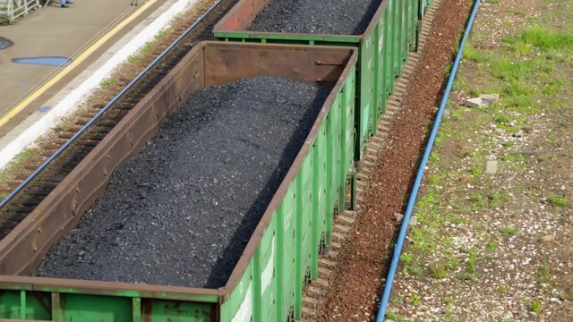 Freight train with coal moving on train station