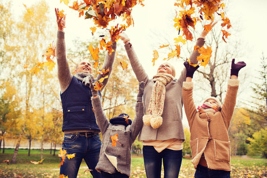 Happy Family Playing With Autumn Leaves In Park