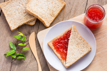Home made bright red strawberry preserves, spread over a slice o