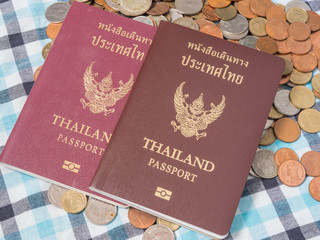 Passport of Thailand  on the pile of coins baht currency, on the loincloth silk background.