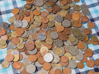 Pile of disrupted coins Baht currency on the loincloth silk background.