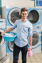  young man holding a laundry basket in launderette