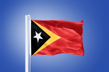 Flag of East Timor flying against a blue sky