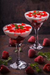 Yogurt with strawberry jelly in a glass glass, on a dark background.