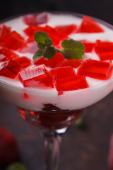 Yogurt with strawberry jelly in a glass glass, on a dark background.