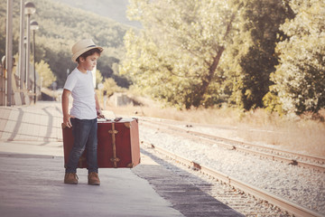 niño con maleta esperando el tren 