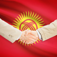 Businessmen handshake with flag on background - Kyrgyzstan