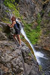 a woman climbing next to a waterfall