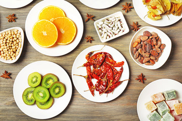 Different products on saucers on wooden table, top view