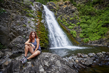 a woman sitting in front of a waterfall
