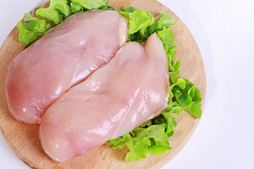 Raw chicken breast fillets  decorated with salad on wooden cutting board. Diet food, healthy lifestyle