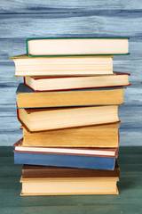 Stack of books on wooden table on blue wooden wall background