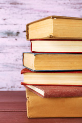 Stack of books on wooden table on pink wooden wall background