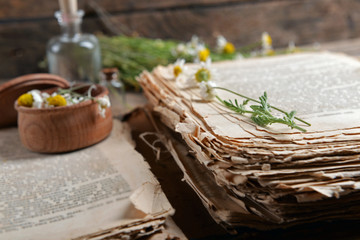 Old book with dry flowers in mortar on table close up