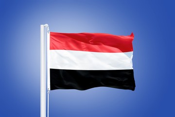 Obraz na płótnie Canvas Flag of Yemen flying against a blue sky