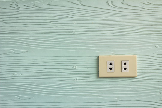 Wall outlets on the pale green wall with wood texture