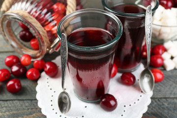 Glasses of sweet homemade cherry compote on table on wooden background