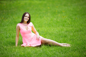 Young spring fashion woman sitting on the grass. Trendy girl in