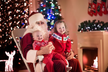 Fototapeta na wymiar Kids and Santa at fire place on Christmas eve