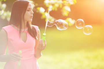 Young spring fashion woman blow bubbles. Trendy girl in the flow