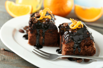 Portion of Cake with Chocolate Glaze and orange on plate, on wooden background