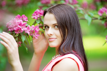 Young spring fashion woman. Trendy girl in the flowering trees in the spring summer garden. Springtime or summertime. Lady in spring landscape background. Allergic to pollen of flowers. Spring allergy