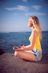 Fototapeta na wymiar Beautiful young blond woman meditating on a beach at sunrise in