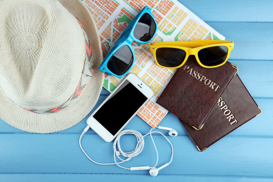 Sunglasses, passports, hats and map on color wooden background. Preparing for travel concept