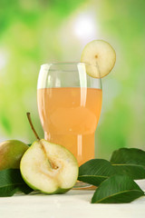 Glass of juice with fresh pears on wooden table on blurred background