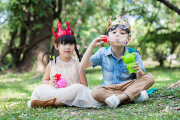 Asian little girl and boy is blowing a soap bubbles