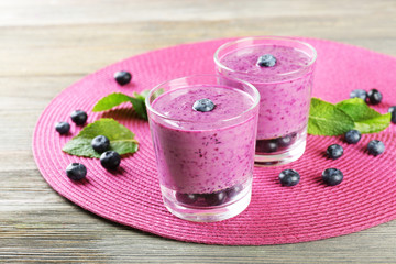 Glasses of blueberry smoothie on pink mat, closeup