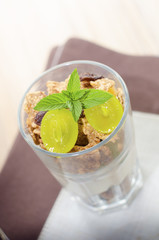 Glass of cornflakes and grapes with mint on a top
