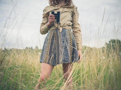 Woman with binoculars standing in meadow