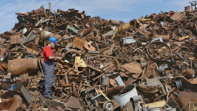 Metal recycling, worker using phone to calculate price and quantity