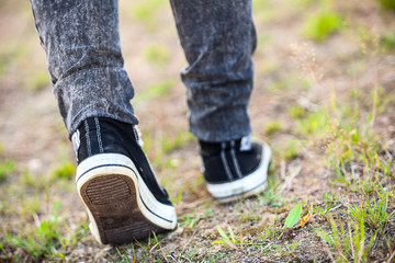 Unrecognizable man in rubber shoes stepping on footpath, rear view, close-up