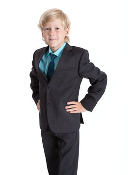 Seven years old blond schoolboy in school uniform, shirt and tie, hands on hips, isolated on white background