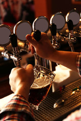 Bartender is pouring beer into glass