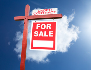 For Sale sign for home in front of blue sky