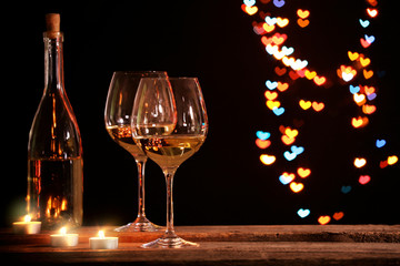 Wine glass near bottle on hearts bokeh background