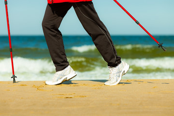 Plakat Nordic walking. Female legs hiking on the beach.