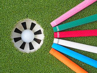 Colorful golf grips point to the hole with ball