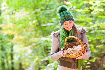 Frau mit Korb voller Pilze beim Sammeln im Wald © Kzenon
