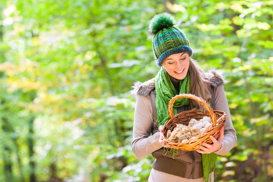 Frau mit Korb voller Pilze beim Sammeln im Wald