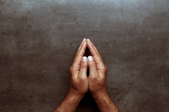 Pray, man hands on grey table background