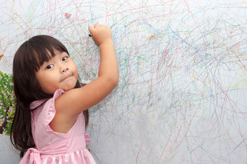 girl drawing with crayons on the wallpaper