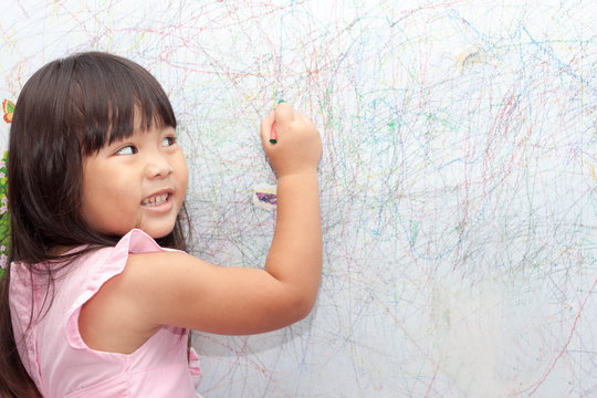 girl drawing with crayons on the wallpaper